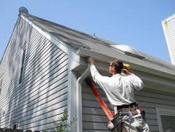 Gutter service professional repairing the gutter on the side of a 2nd story roof.